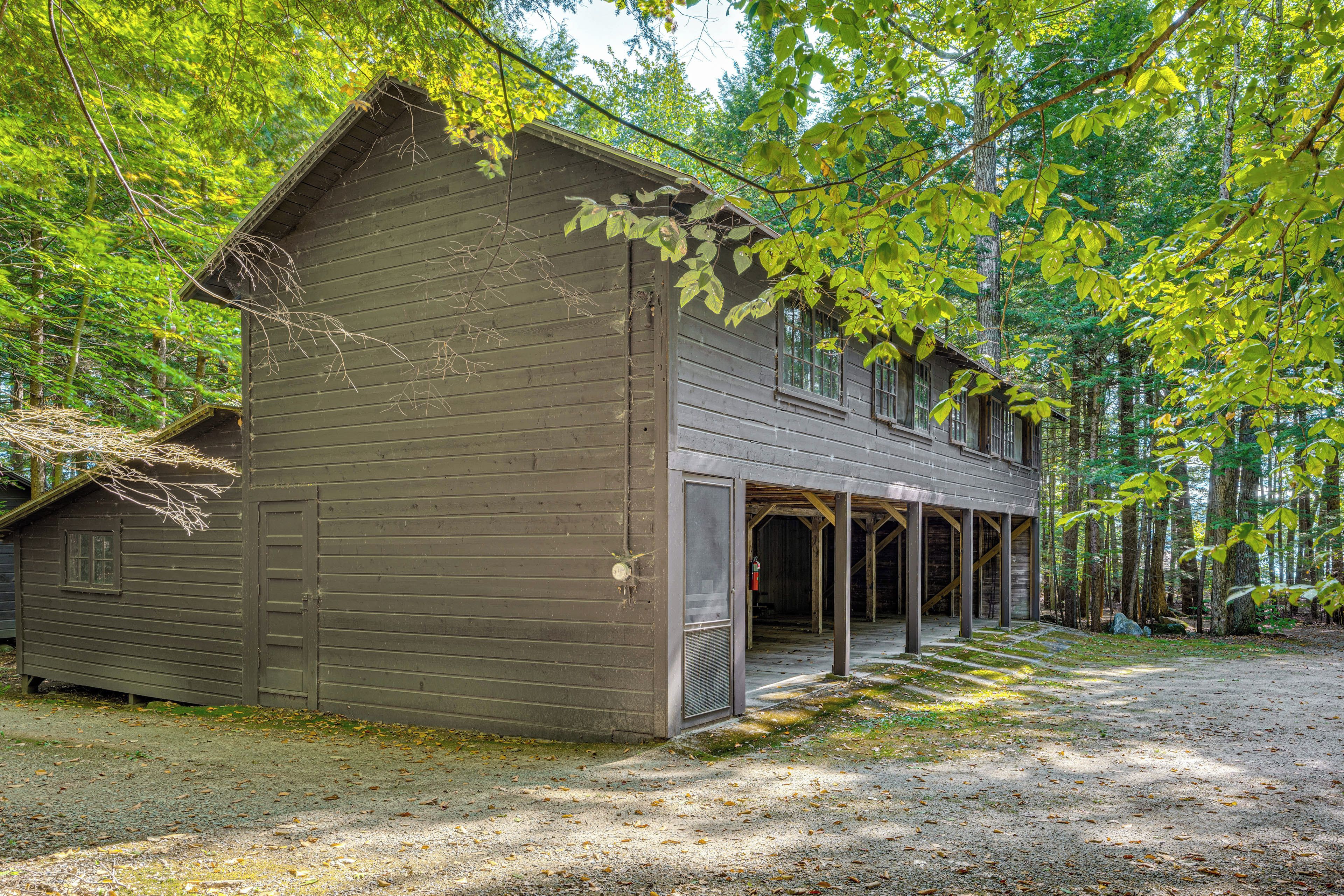 A rustic wooden cabin with a porch, surrounded by a forest.