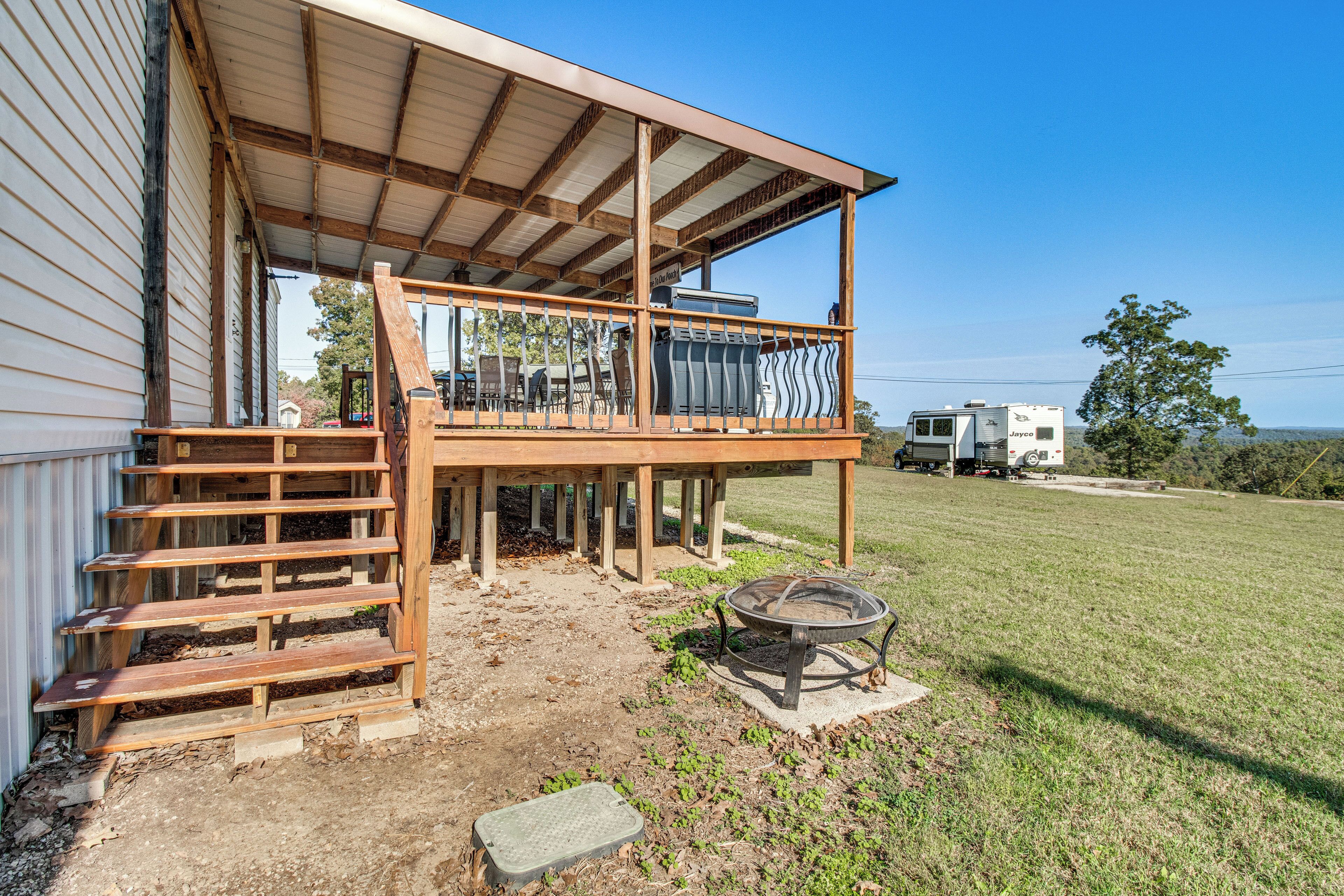 A two-story building with a balcony, a fire pit, and an RV in the background.