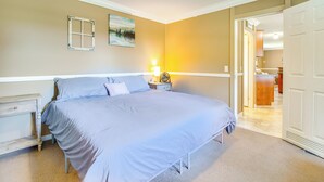 A bedroom with a bed, nightstands, a lamp, and a door leading to another room. - Lake-view Getaway w/ Grill in Mountain Home! (Mountain Home)