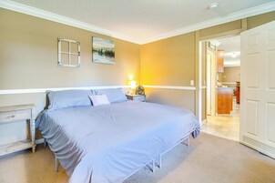 A bedroom with a bed, nightstands, a lamp, and a door leading to another room.