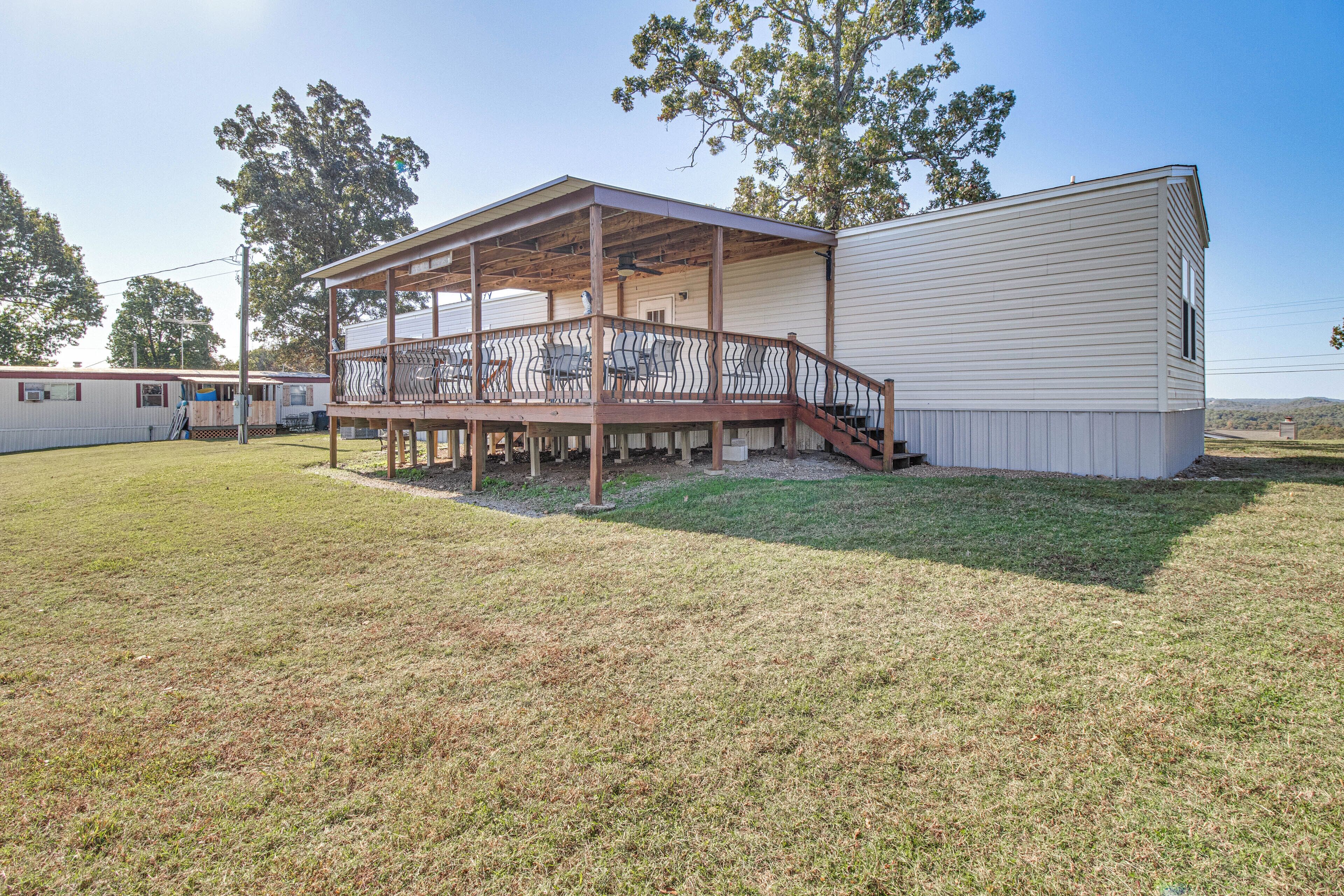 A mobile home with a covered porch and a fenced deck area.