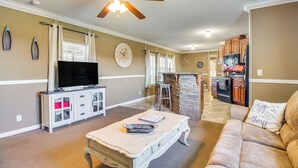 A living room with a television, a dining area with a table, and a kitchen in the background. - Lake-view Getaway w/ Grill in Mountain Home! (Mountain Home)