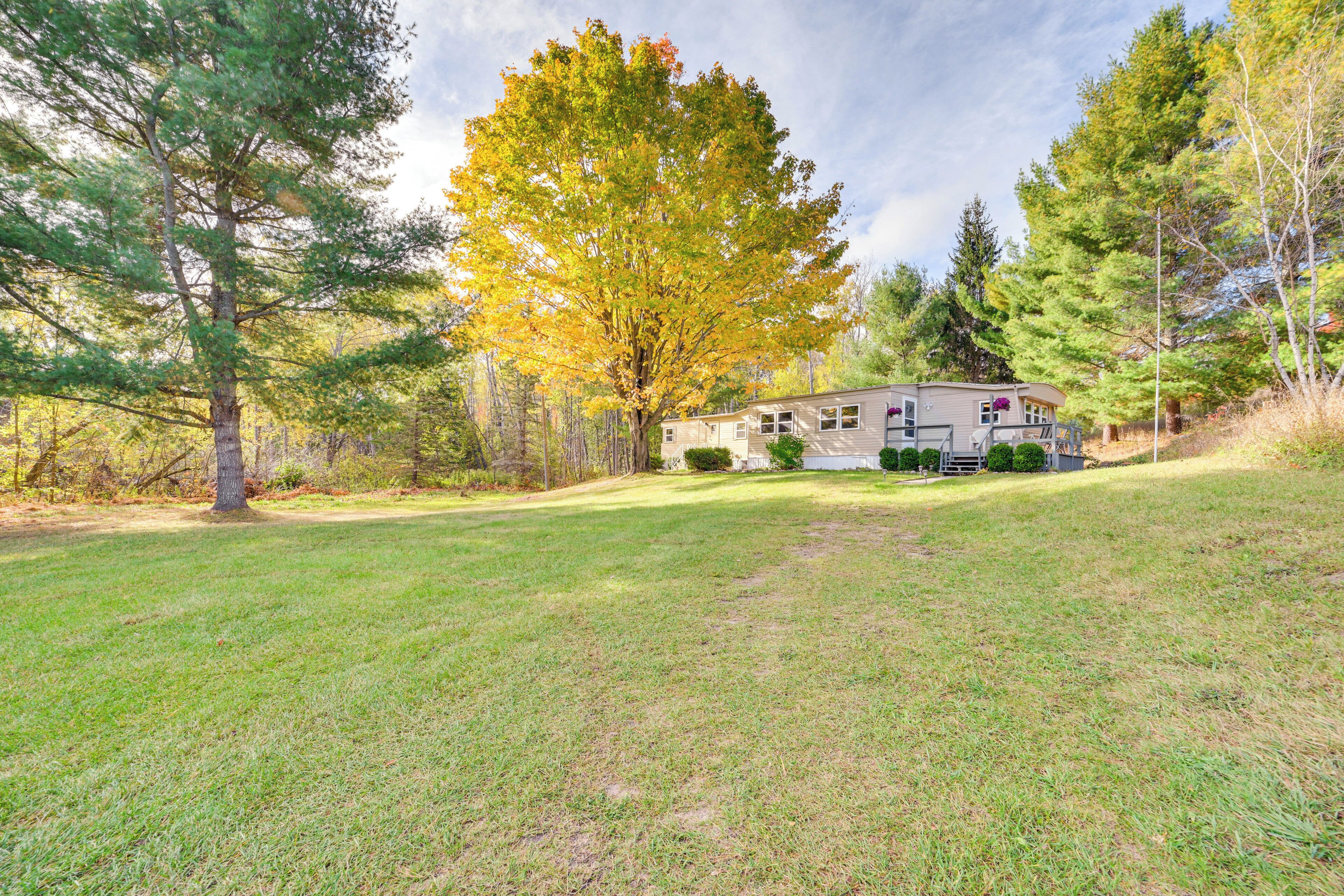 A single-story house with a front yard, surrounded by trees and a clear sky.