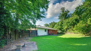 A backyard with a paved patio, a small brick building, and a well-maintained lawn.
