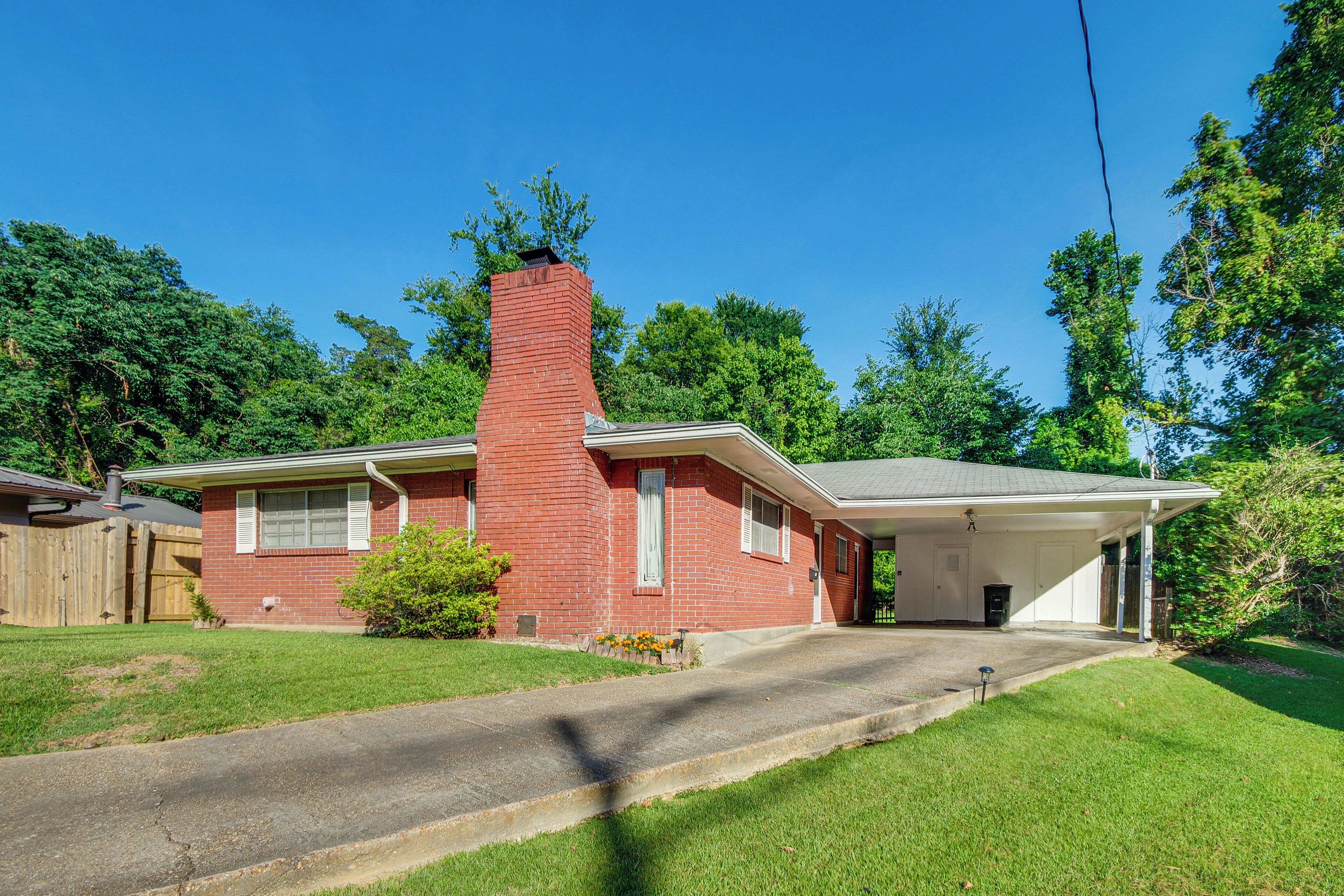 A single-story brick house with a chimney, a garage, and a covered driveway.