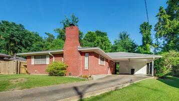 A single-story brick house with a chimney, a garage, and a covered driveway.