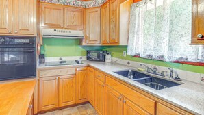 A kitchen with wooden cabinets, a microwave, an oven, and a sink.