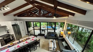 Eine moderne Küche mit Essbereich, einer Sofagarnitur und Blick auf Pool und Grünflächen.