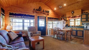 Un interior acogedor de cabaña con sala de estar, comedor y cocina.