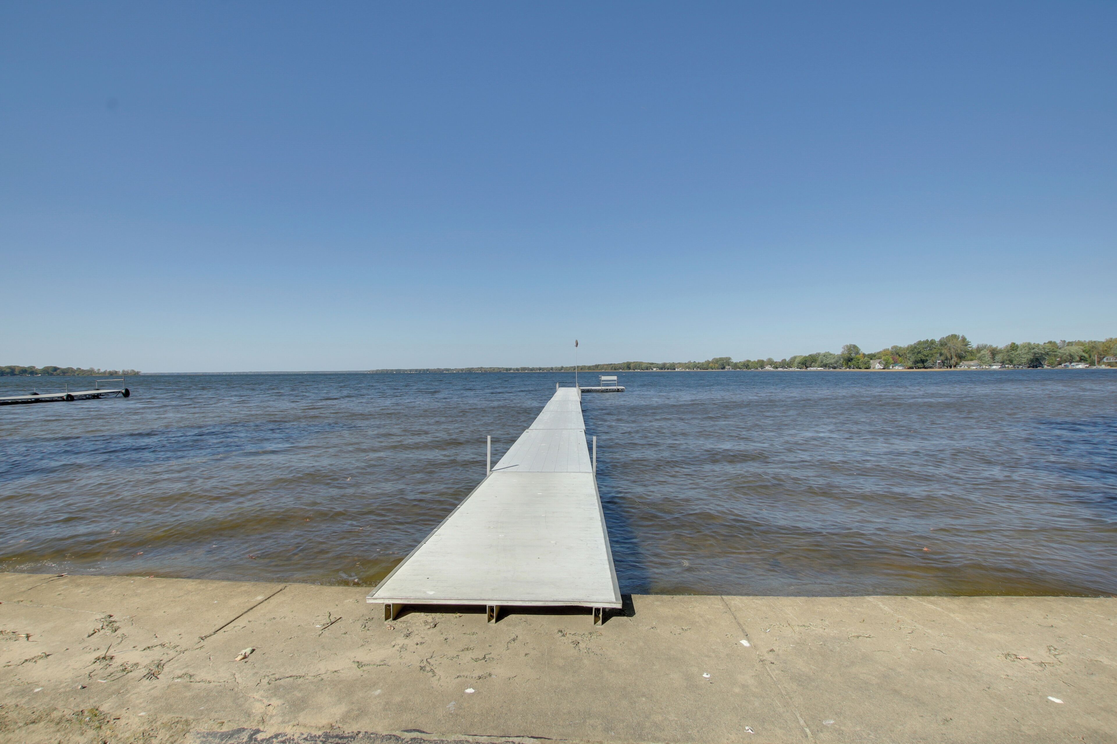 Un pilier de béton s’étendant dans une étendue d’eau calme, sous un ciel dégagé.
