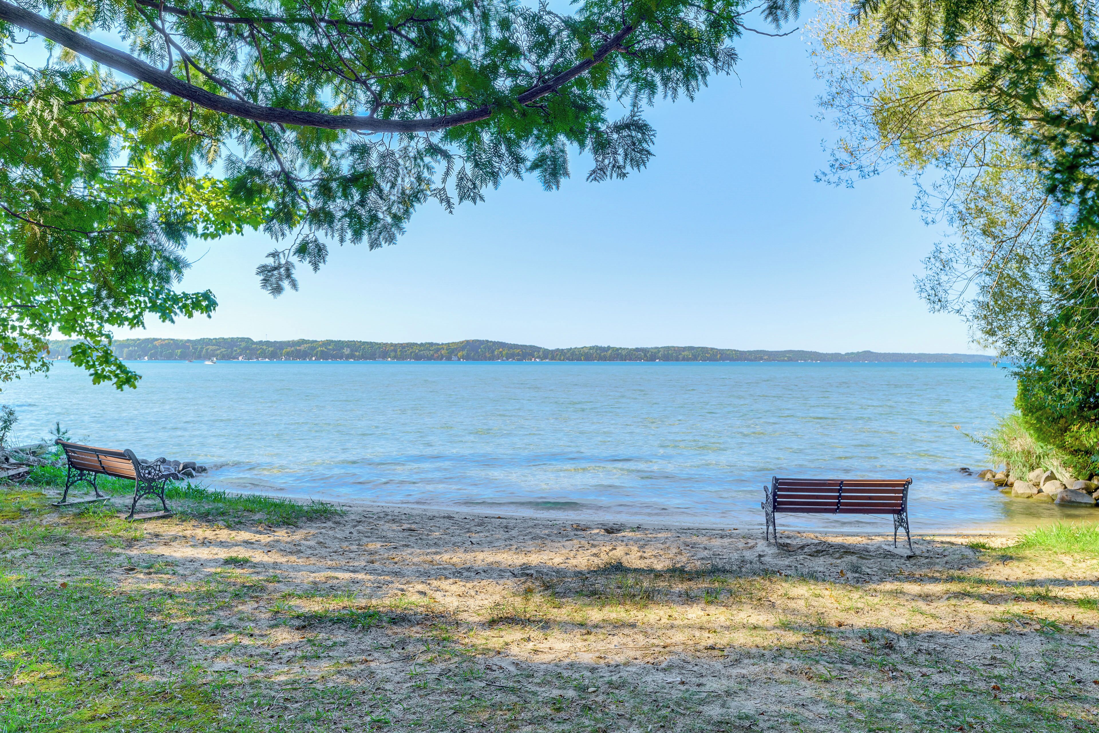 A bench by a lake with a clear view of the water and distant hills.