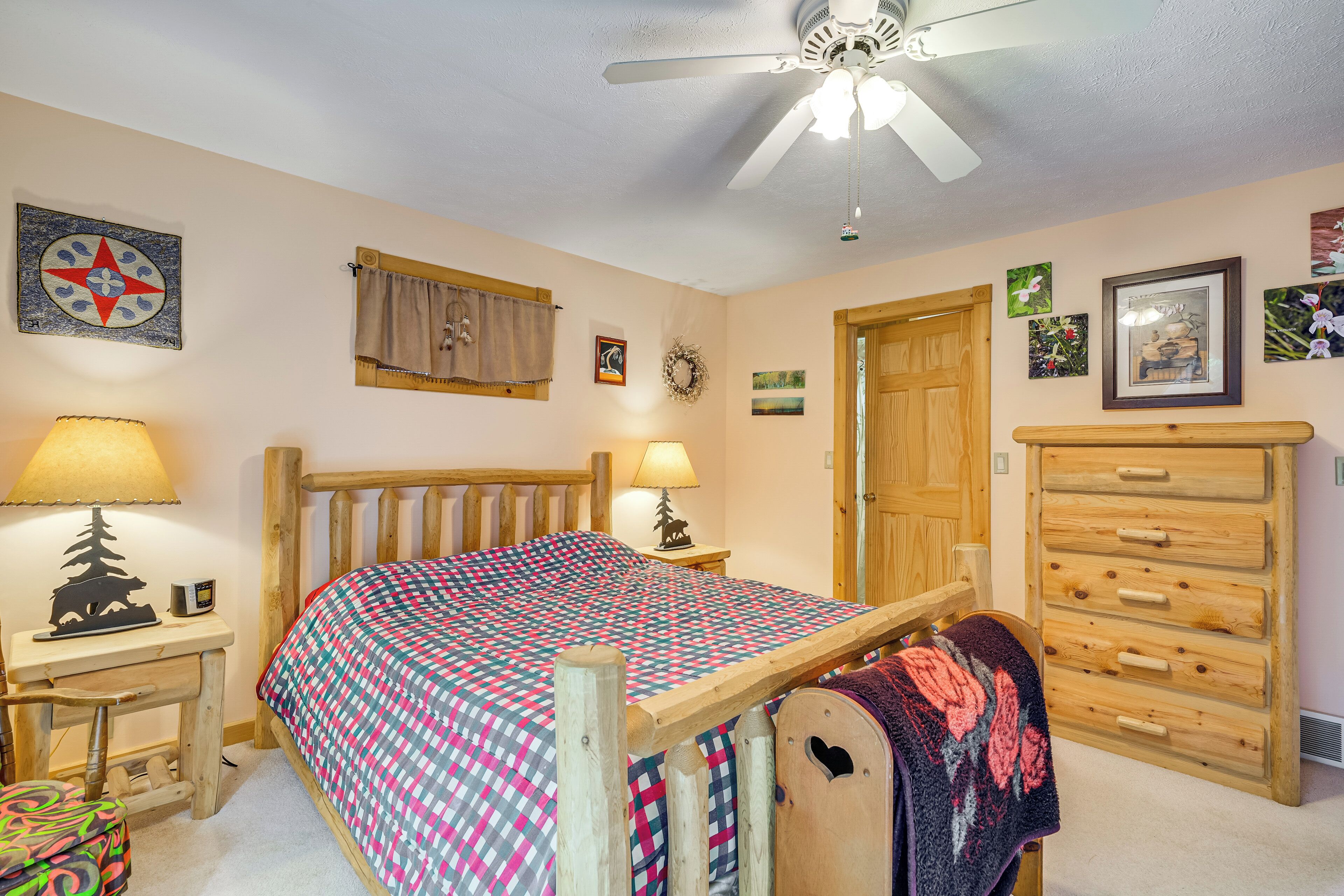 A bedroom with a wooden bed, two bedside tables with lamps, a dresser, and a ceiling fan.