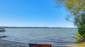 Un banco junto a un lago con agua tranquila y colinas al fondo.