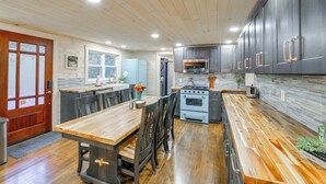 Una cocina moderna con suelo de madera, una isla central, armarios oscuros y electrodomésticos de acero inoxidable.