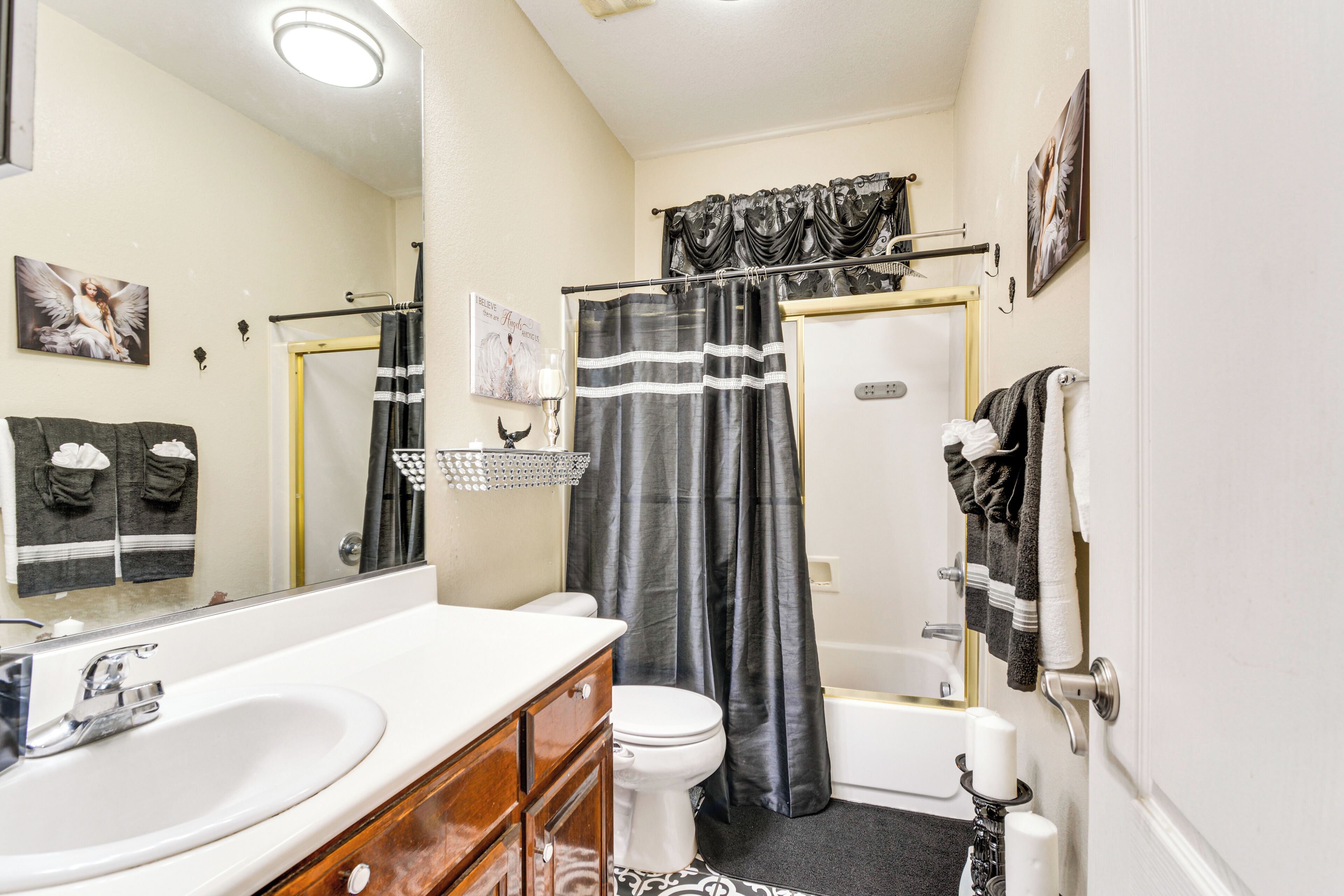 A bathroom with a white sink, vanity, toilet, and bathtub.