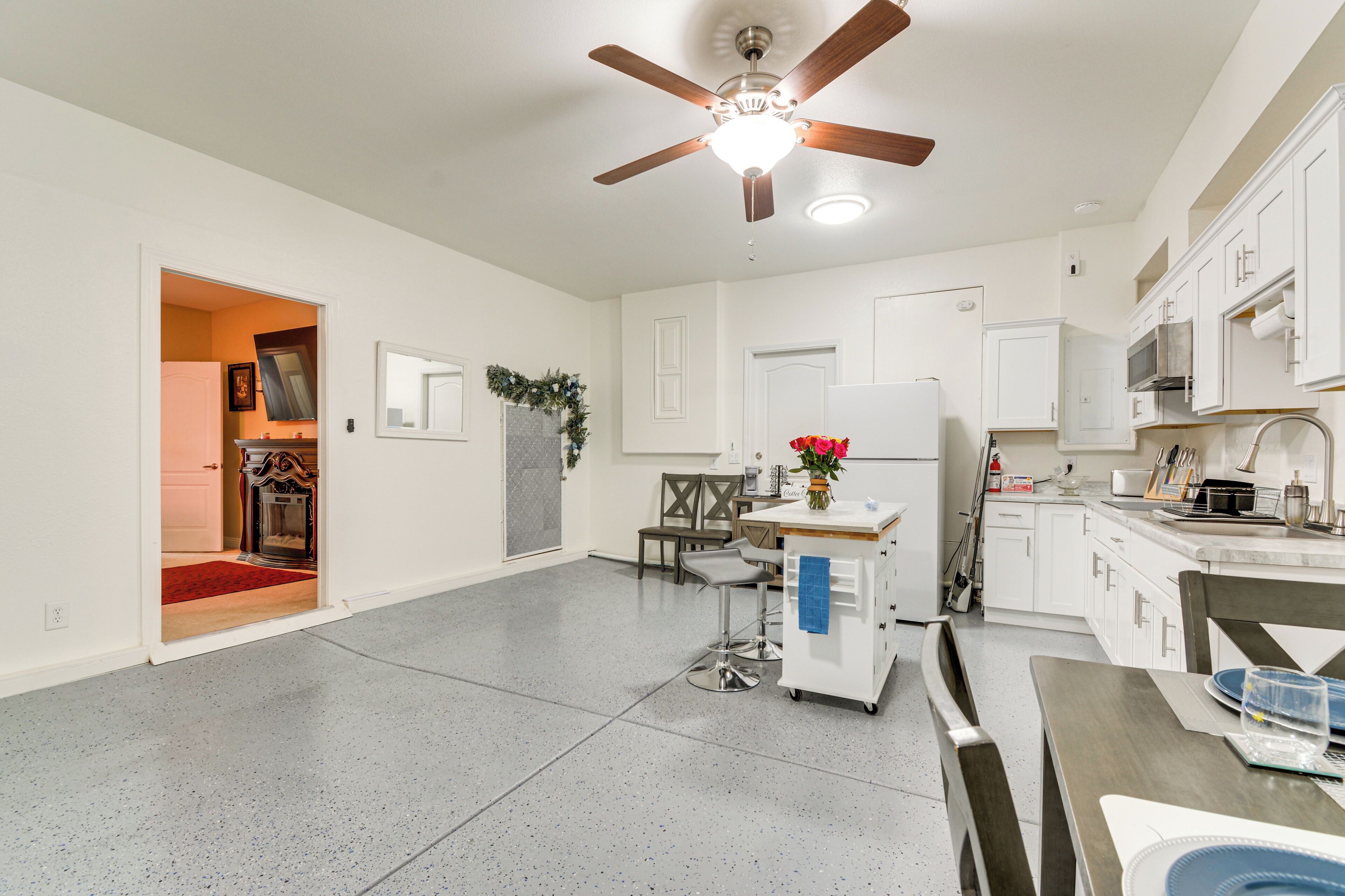 A spacious kitchen with white cabinets, a ceiling fan, and a dining area with a table and chairs.