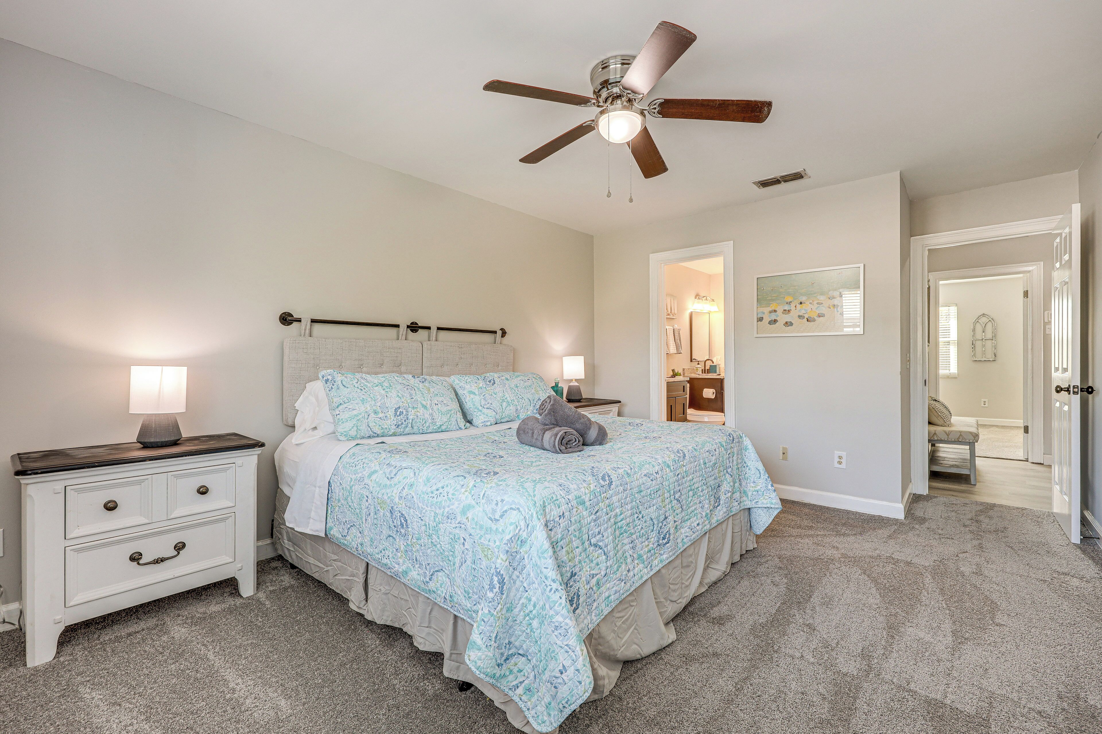 A bedroom with a bed, nightstand, and ceiling fan.