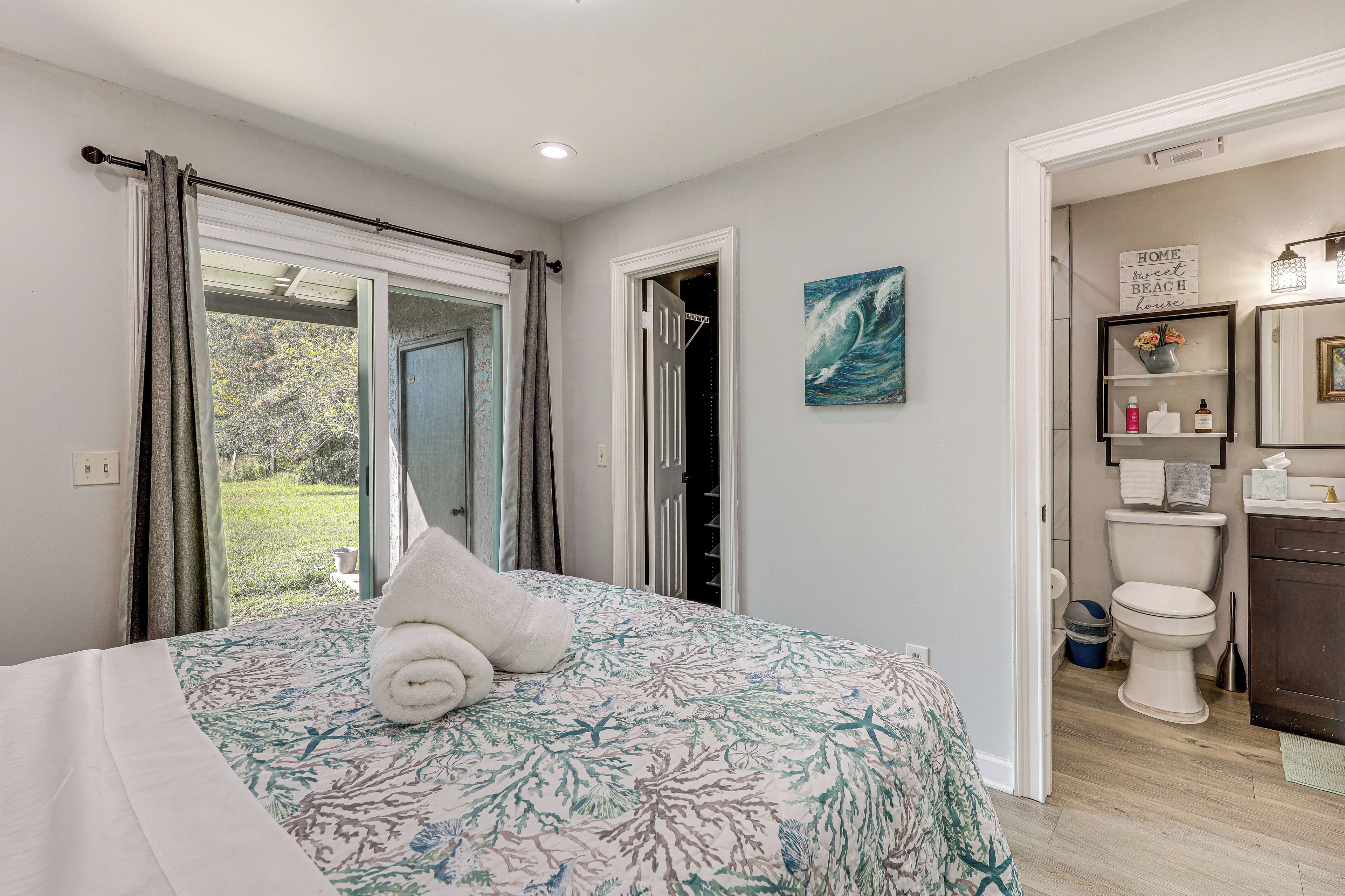 A bedroom with a bed, a bathroom with a toilet, and a view of the outdoors.