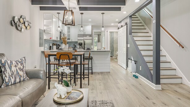 A modern kitchen with a central island, a dining area with a sofa and chairs, and a staircase leading to an upper level. - Ponte Vedra Beach Getaway w/ Patio! (Ponte Vedra Beach)