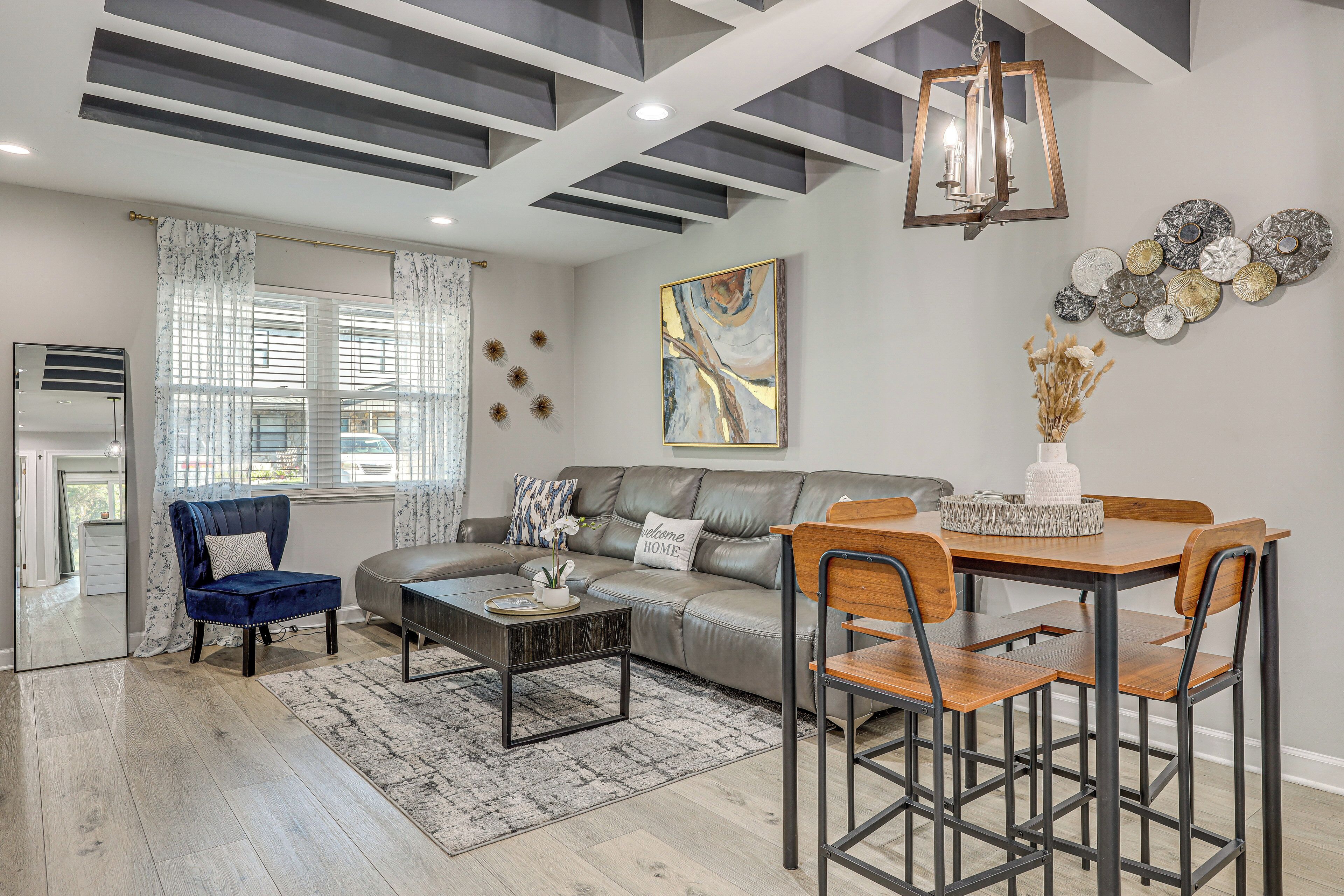 Een moderne woonkamer met een modulaire bank, een salontafel, een eettafel met stoelen en decoratieve wandkunst.