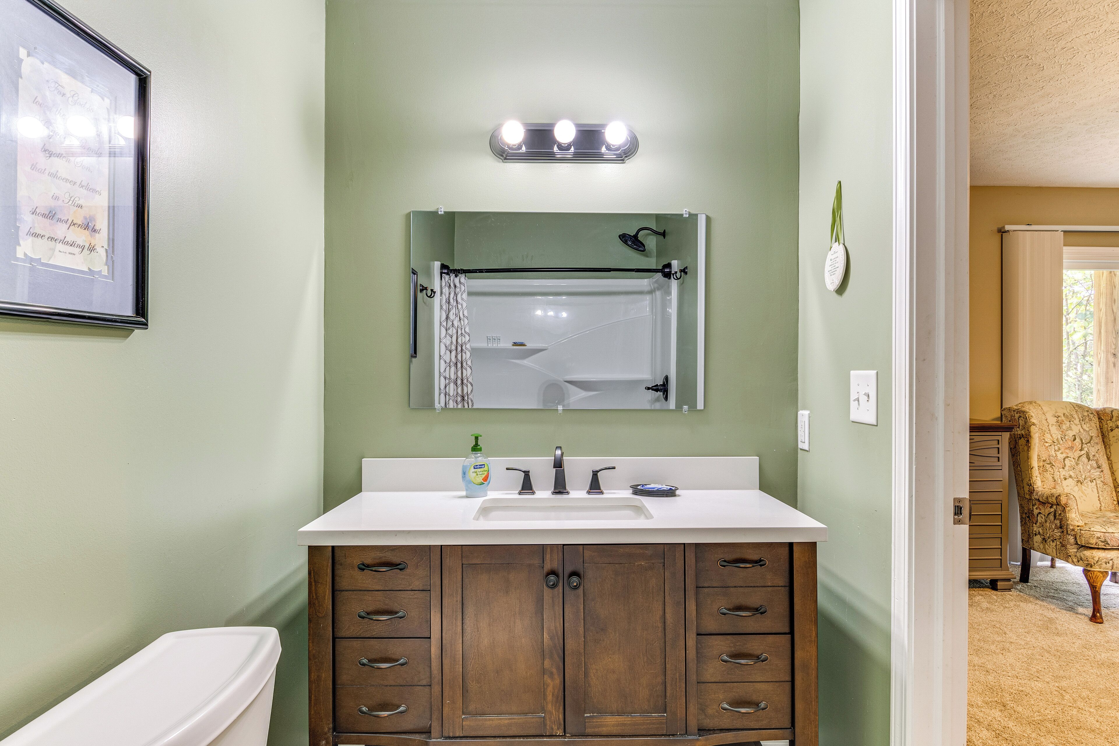A bathroom with a white sink, wooden vanity, and a mirror above the sink.