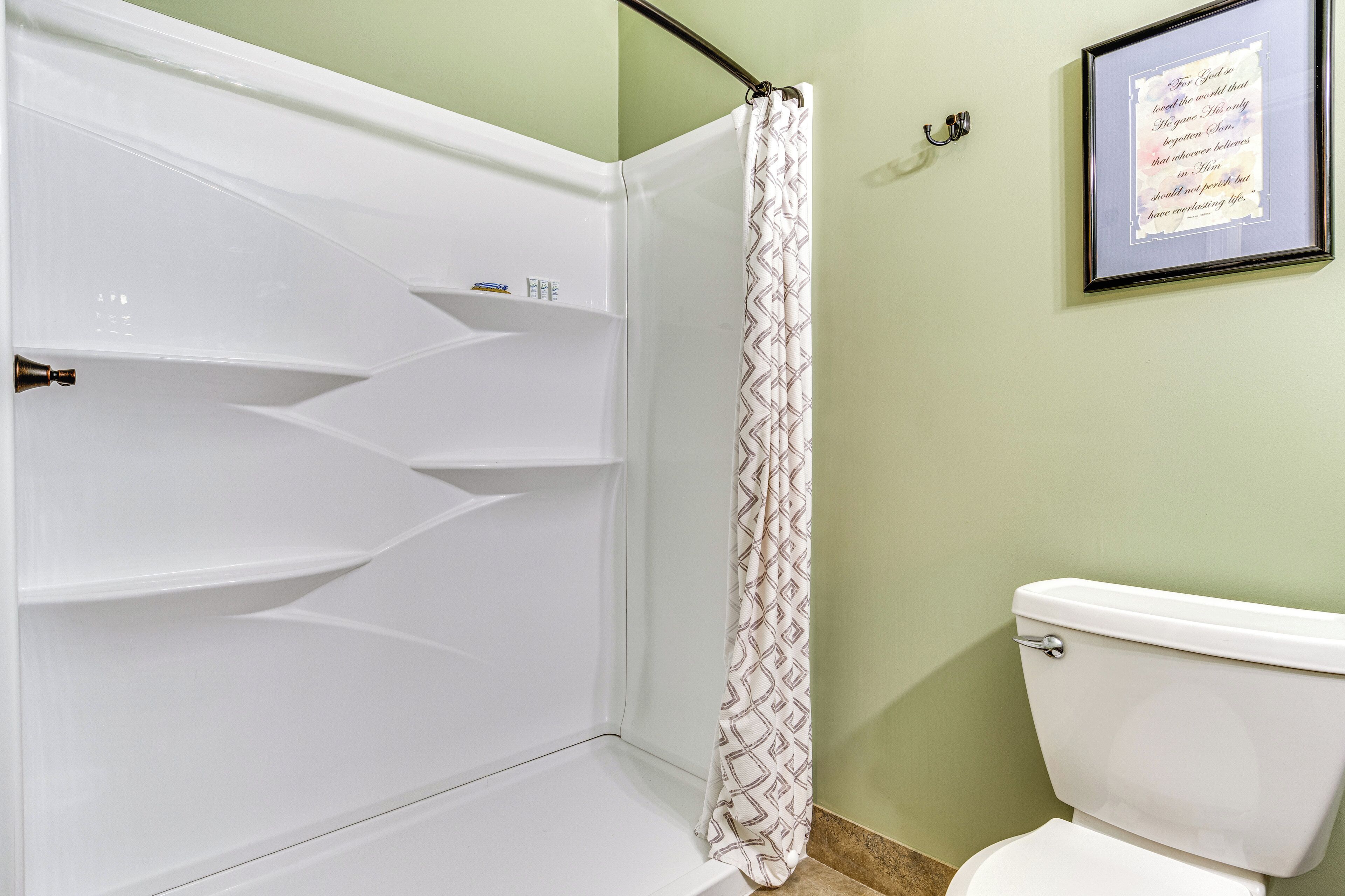 Ein Badezimmer mit Dusche, Toilette und einem gerahmten Zitat an der Wand.