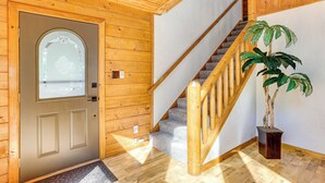 A wooden interior with a door, a staircase, and a potted plant.