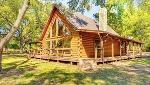A log cabin with a porch, large windows, and a chimney.