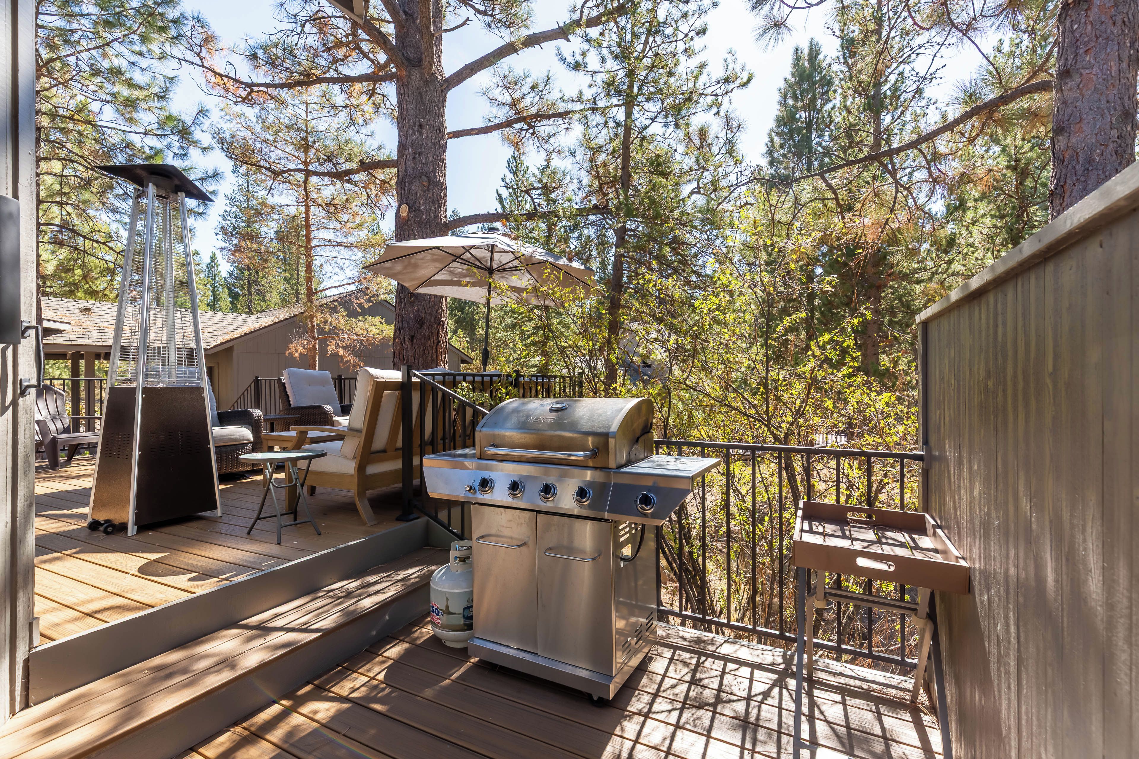 An outdoor deck with a barbecue grill, seating area, and a pergola with an umbrella.