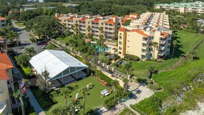 A multi-story hotel with a central courtyard, surrounded by lush greenery and palm trees. - King and Prince Villa (St. Simons Island)
