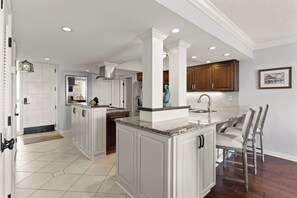 A spacious kitchen with white cabinetry, a granite countertop, and a large island. - King and Prince Villa (St. Simons Island)