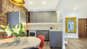 A modern kitchen with a brick wall, grey cabinets, a built-in oven, and a small island with a sink.