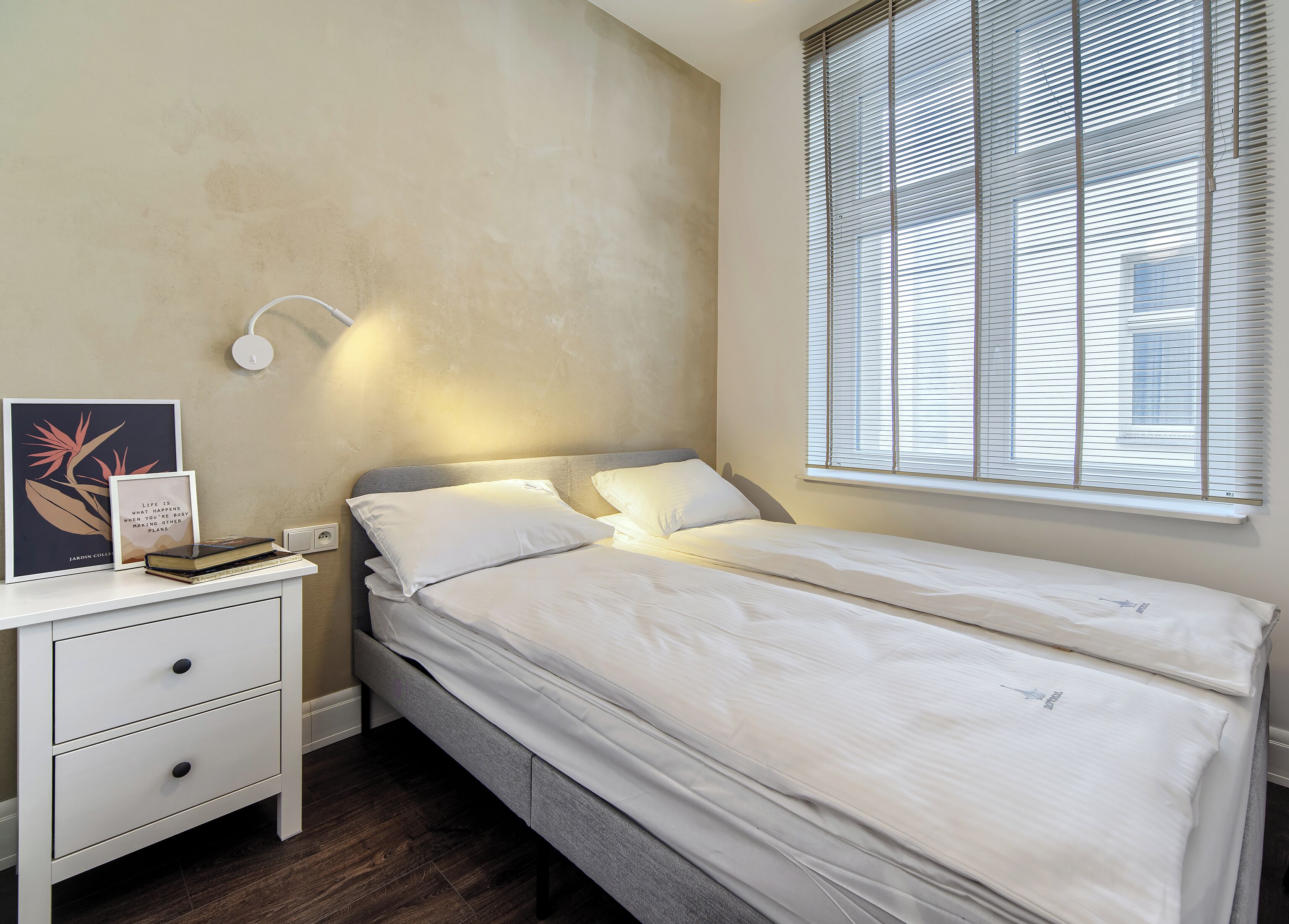 Ein ordentlich eingerichtetes Schlafzimmer mit Bett, Nachttisch und einem Fenster mit Jalousien.