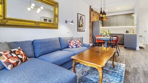 A modern living room with a blue sofa, a wooden coffee table, and a large mirror.