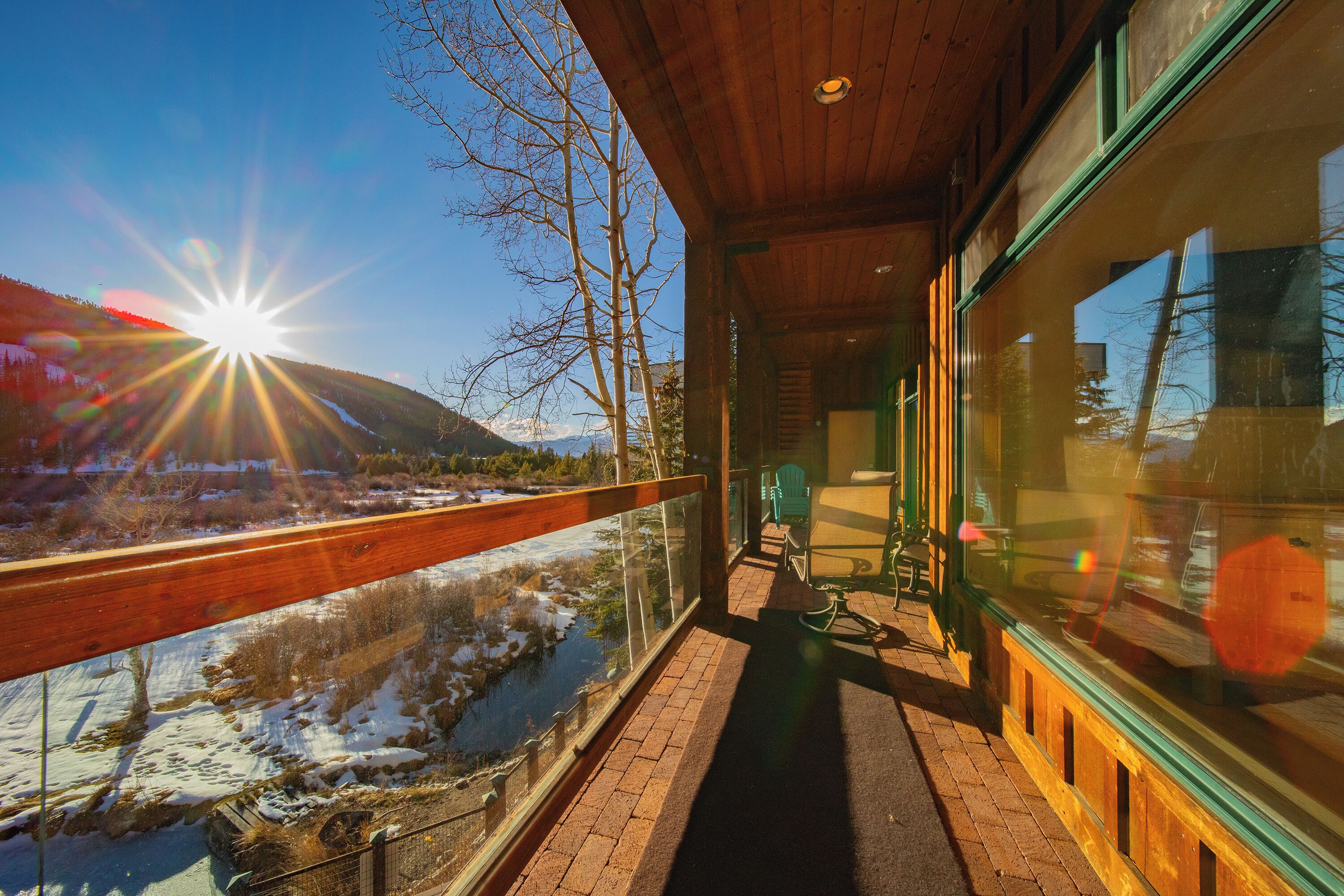 Un balcon en bois offrant une vue sur une rivière et des montagnes.
