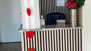 Ein Empfangsschalter mit vertikalem Streifenmuster, eine Vase mit roten Blumen und einer herzförmigen Dekoration.