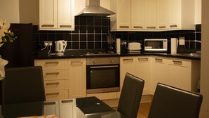 Una cocina moderna con armarios blancos, salpicadero negro y electrodomésticos de acero inoxidable.