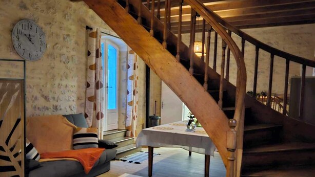 A wooden staircase in a room with a sofa, a table, and a clock on the wall. - Former gatehouse, spa, billiards room near Beauval Zoo, Loire château. (Luçay-le-Mâle)