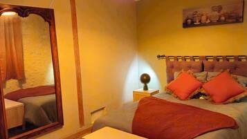 Quarto com cama, mesa de cabeceira, luminária, espelho e luminária pendente.