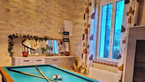 A pool table with pool cues and balls, a hanging light fixture, a mirror, and a window with curtains. - Former gatehouse, spa, billiards room near Beauval Zoo, Loire château. (Luçay-le-Mâle)