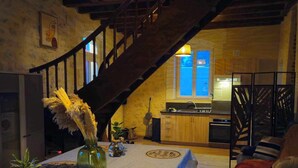 A cozy living room with a staircase, a dining table with place cards, and a kitchen in the background. - Former gatehouse, spa, billiards room near Beauval Zoo, Loire château. (Luçay-le-Mâle)
