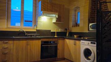 Une cuisine moderne avec des meubles en bois, un four encastré, un lave-linge et une grande fenêtre offrant une belle vue.
