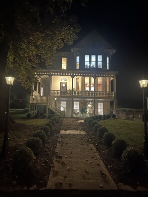 A large, two-story building with a balcony and a covered porch, illuminated by street lamps. - Historic Victorian home in Singers Glen  (Singers Glen)