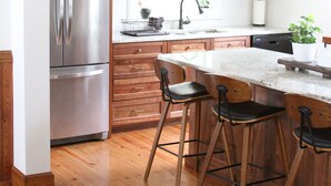 Una cocina moderna con armarios de madera, electrodomésticos de acero inoxidable y taburetes de bar.