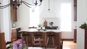 Una cocina con armarios de madera, una isla central con taburetes de bar e iluminación colgante.