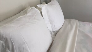 Una cama bien tendida con sábanas blancas en una habitación de hotel.