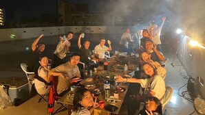 A group of people dining outdoors at night with a table set for a meal, surrounded by city buildings. - One Miyakojima (Miyakojima)