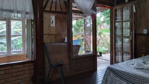 A wooden room with a bed, a chair, and a window with curtains. - ALDEA zen chalés e suítes privativos (Ouro Preto)