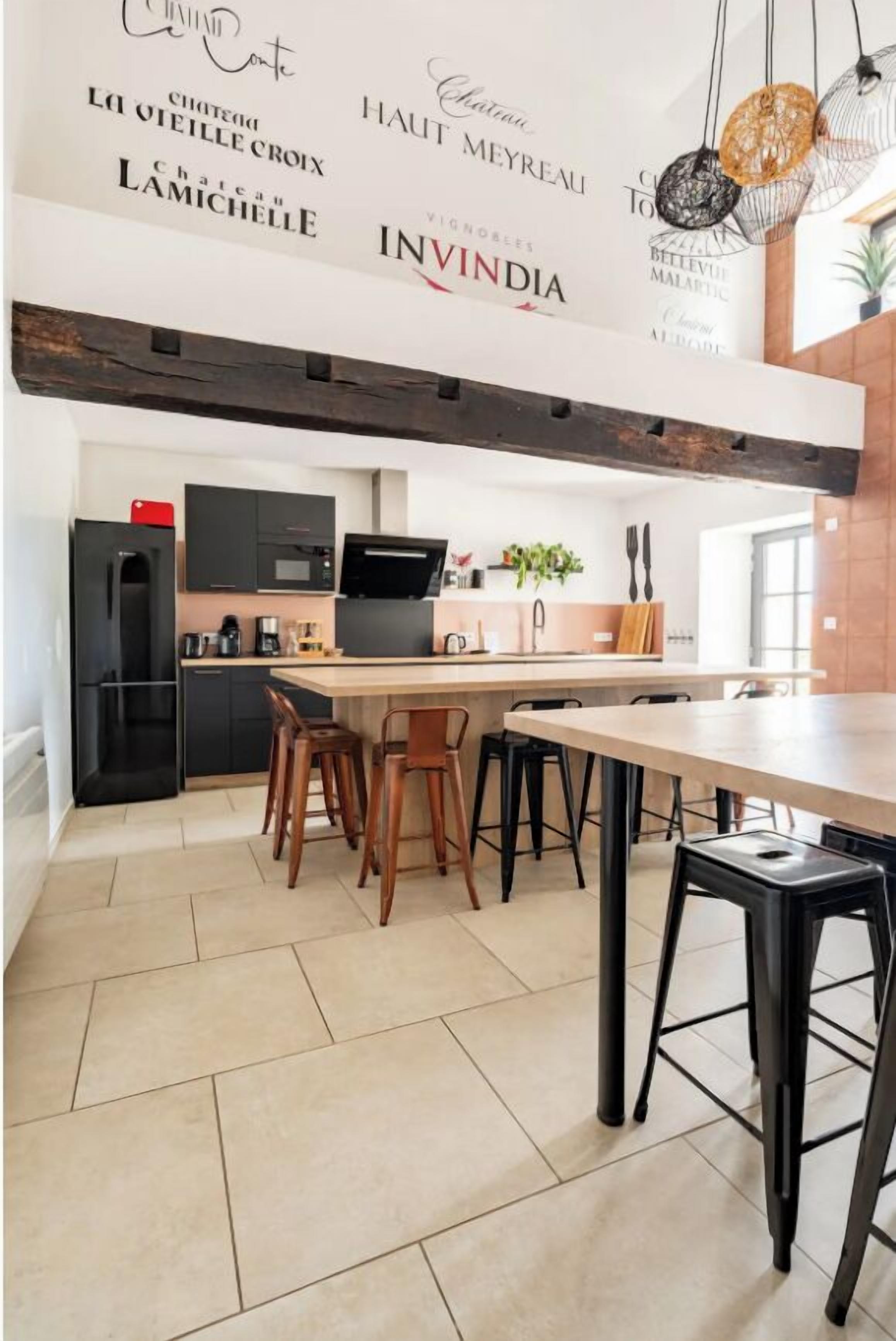 Une cuisine moderne avec un îlot central, des appareils électroménagers noirs et un plancher en bois.