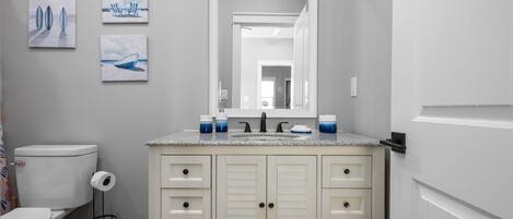 A bathroom with a toilet, sink, and cabinet. There are three framed pictures on the wall.